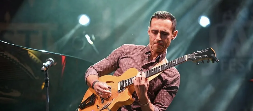 Hristo Vitchev playing an archtop guitar on stage at a jazz festival